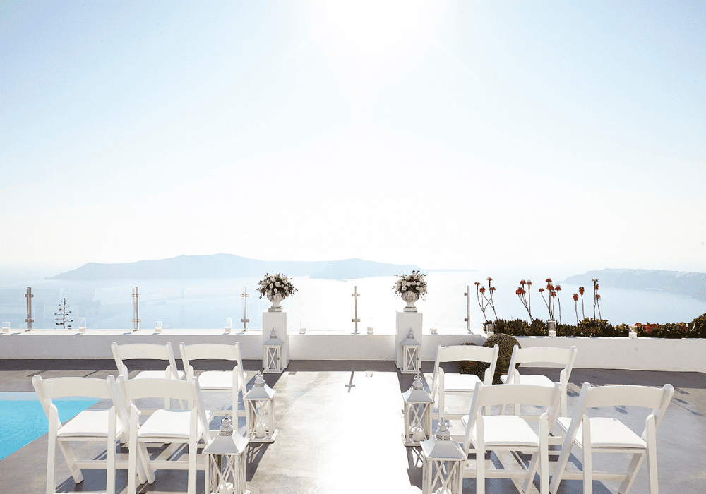A serene wedding ceremony on the terrace at Erossea Villa Santorini, with beautifully arranged chairs and floral decorations