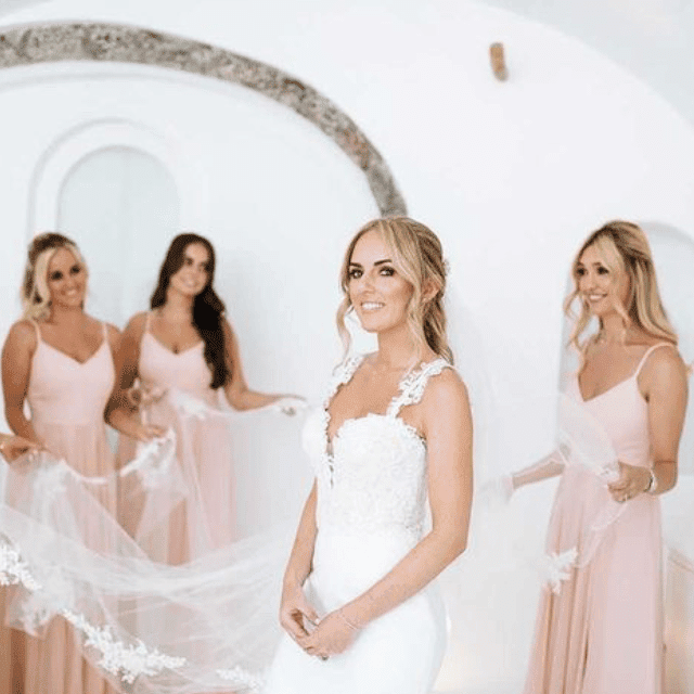 Bridesmaids in elegant pink dresses and veils, celebrating at Erossea Villa during a stunning Santorini wedding