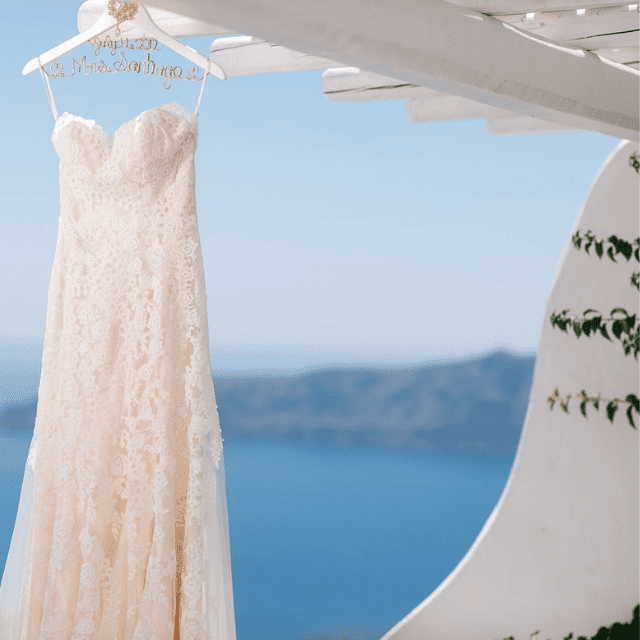 A stunning wedding dress elegantly drapes from a balcony at Erossea Villa, Santorini, capturing a moment of bridal beauty
