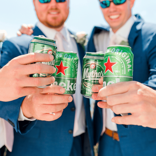 A joyful groom and groomsmen raise Heineken beers in a toast at the elegant Erossea Villa, Santorini, celebrating love