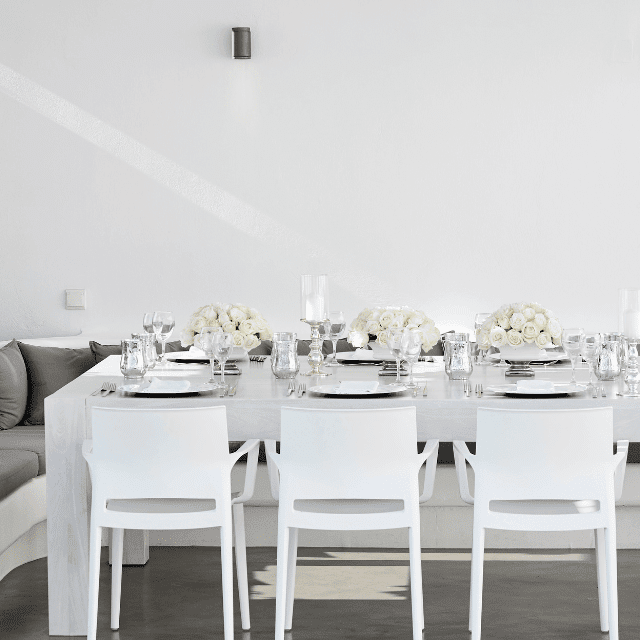 A pristine white table surrounded by matching chairs, embodying the elegance of Erossea Villa for a Santorini wedding