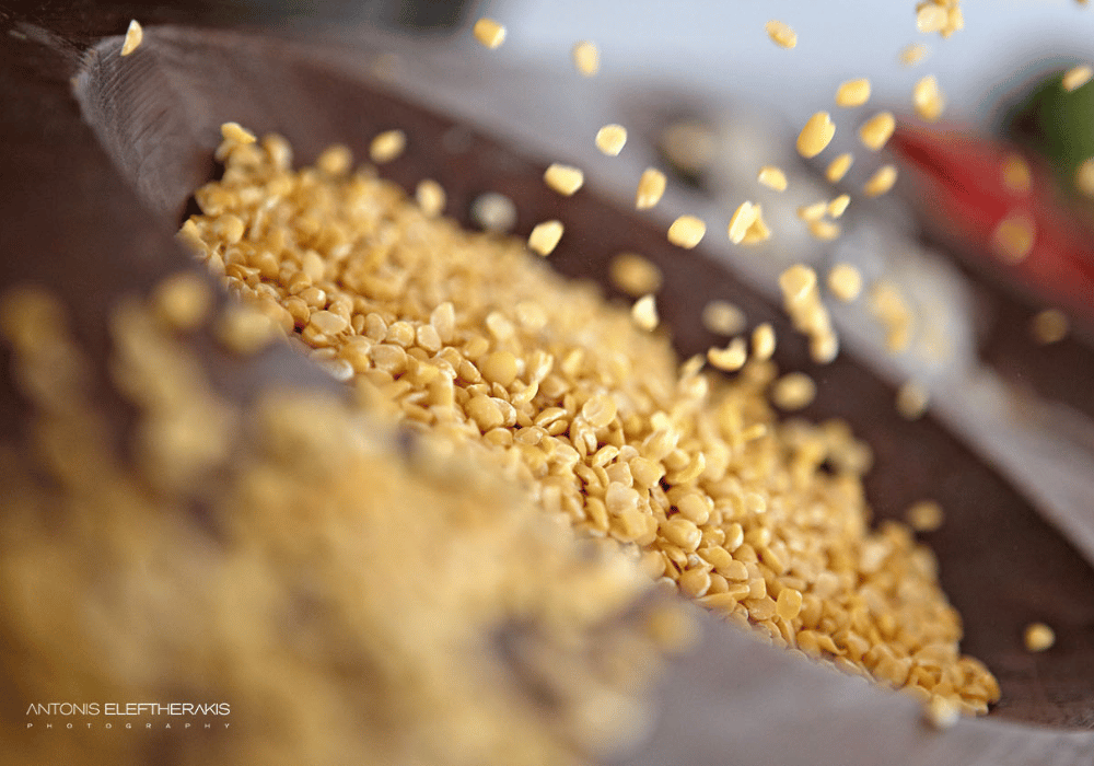 A vibrant bowl of yellow lentils being tossed, showcasing the culinary artistry of Erossea Villa Santorini Private Chef Services