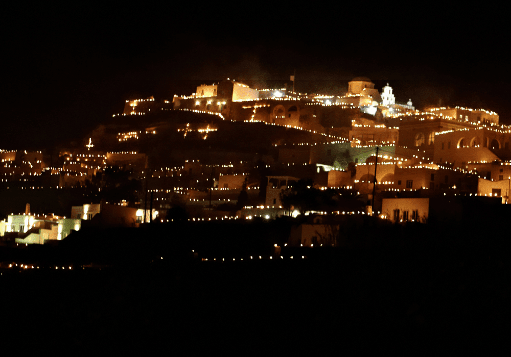 A picturesque city illuminated by candles at night, showcasing Erossea Villa during Greek Easter in Santorini
