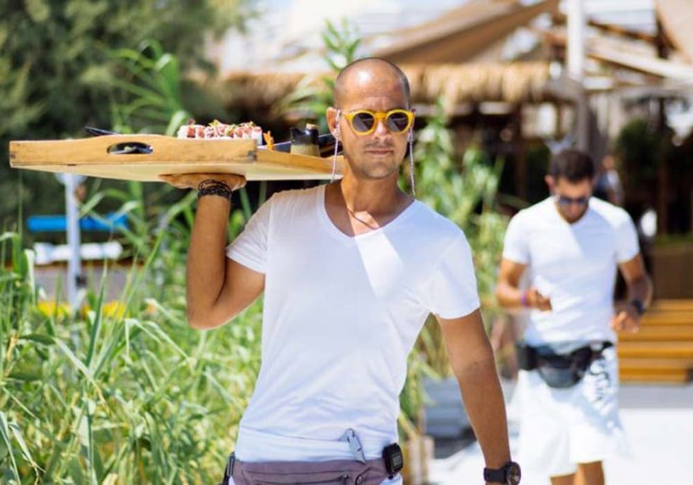 Waiter in Santorini beach bar carrying a platter