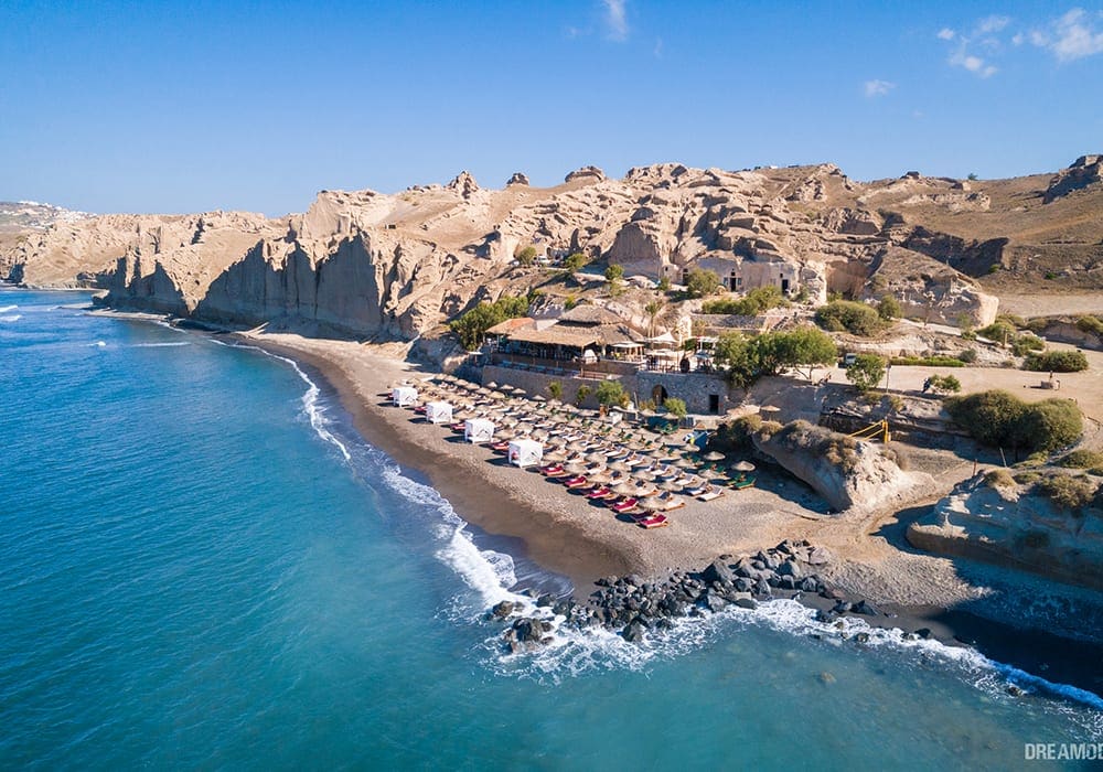 Theros Wave Bar in Vlychada in an an arial view featuring the sand beach and azure waters